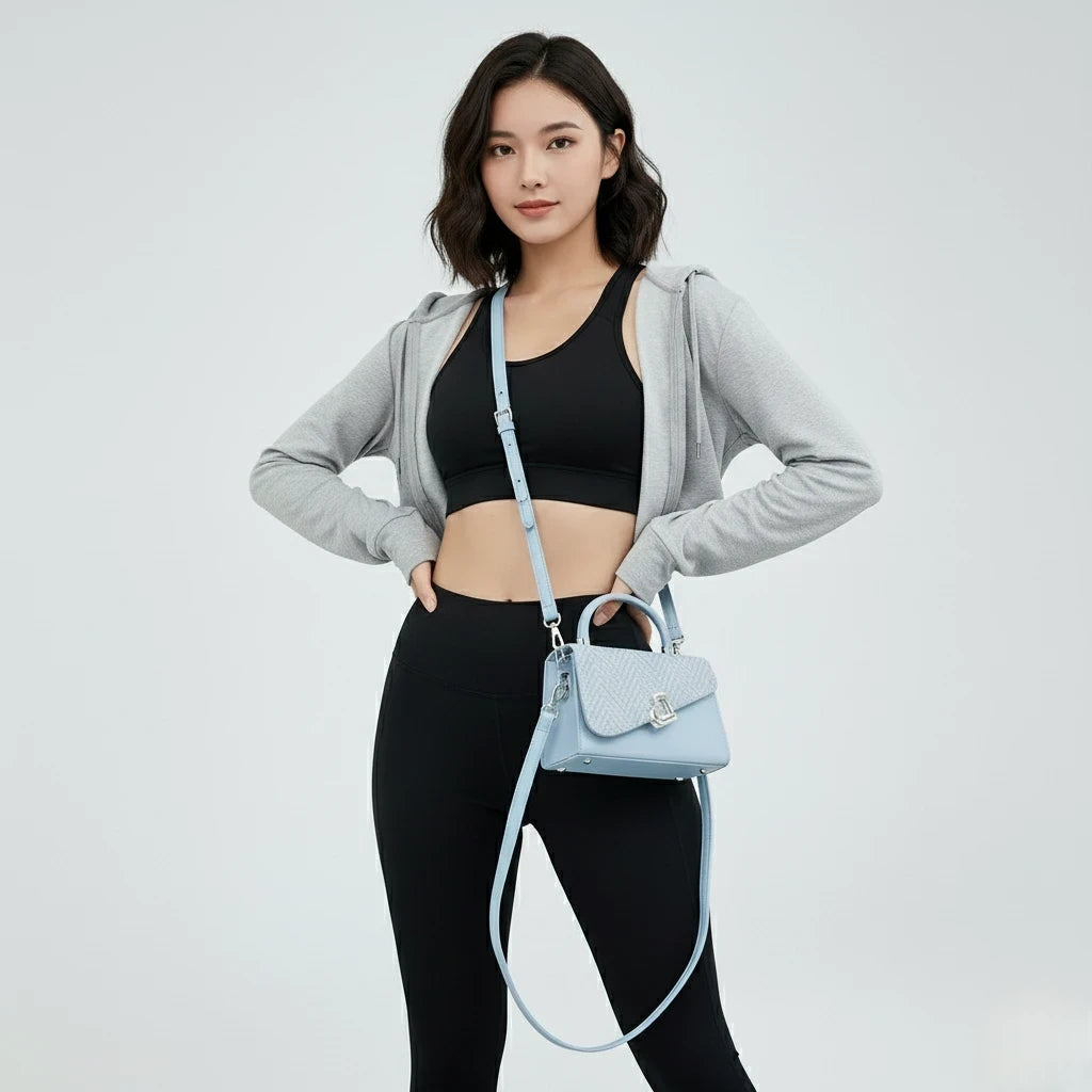Woman holding a light blue handbag against a plain background