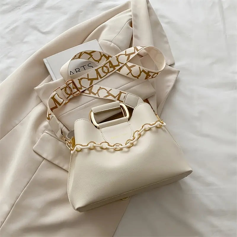 Beige handbag with gold chain detail on a light background