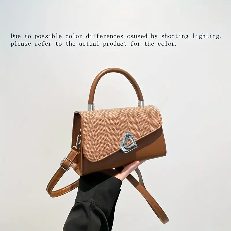 Handbag with woven pattern and brown leather accents held by a person against a plain background.