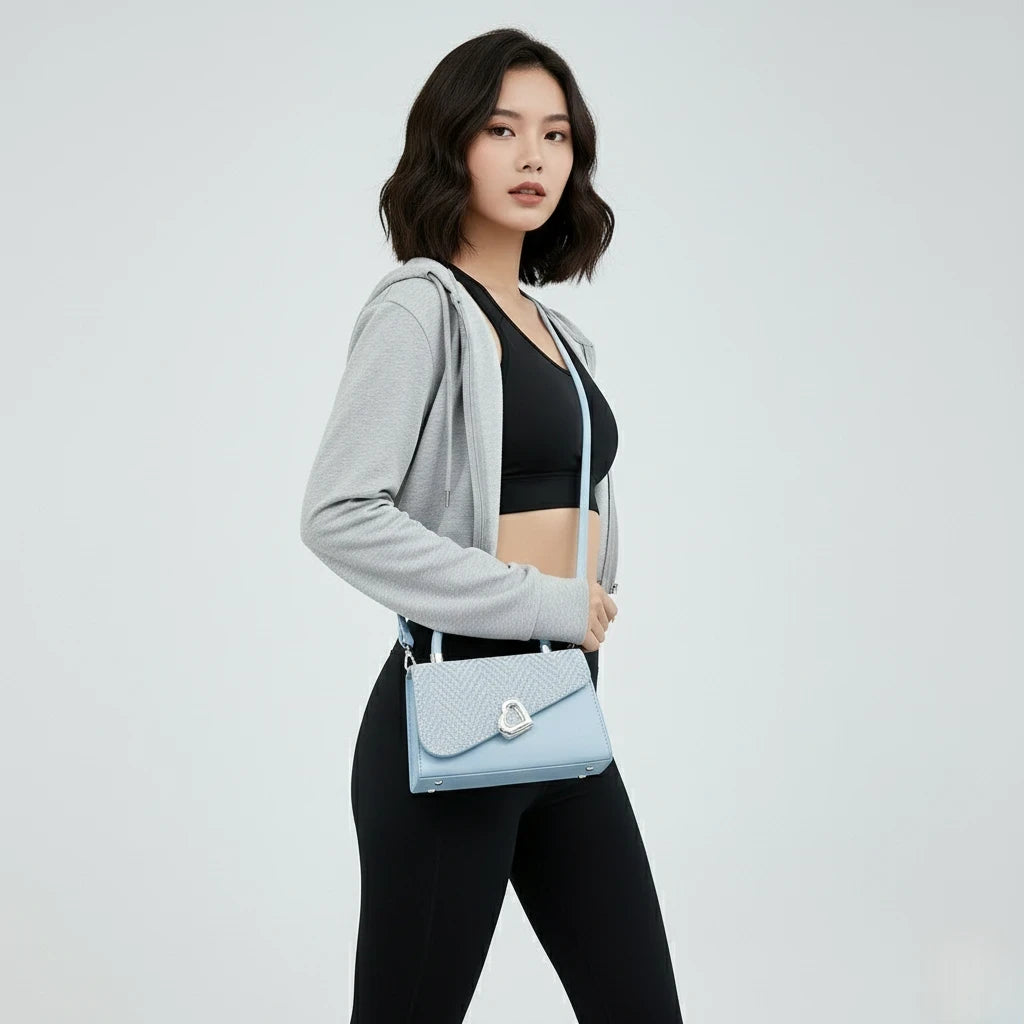 Woman holding a light blue handbag against a plain background