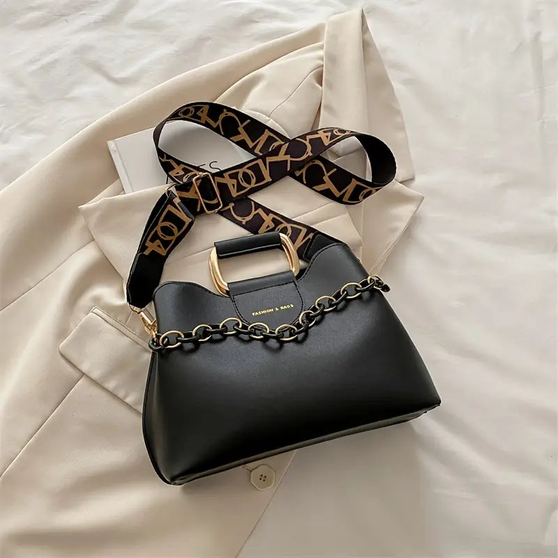 Black handbag with a leopard print strap on a beige jacket