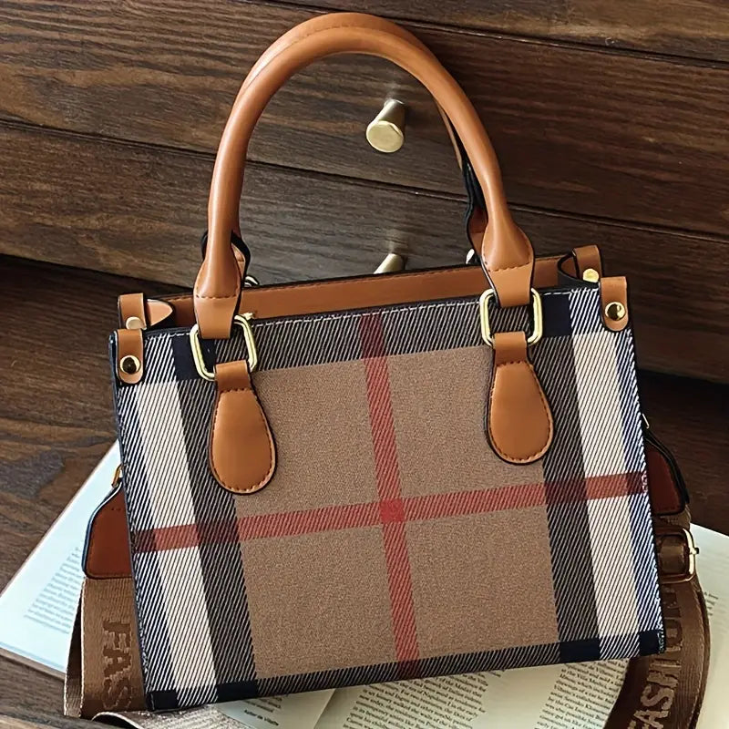 Plaid handbag with brown leather handles and accents on a wooden surface