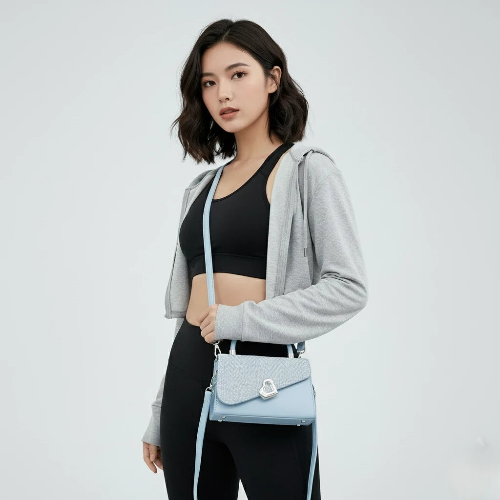 Woman holding a light blue handbag against a plain background