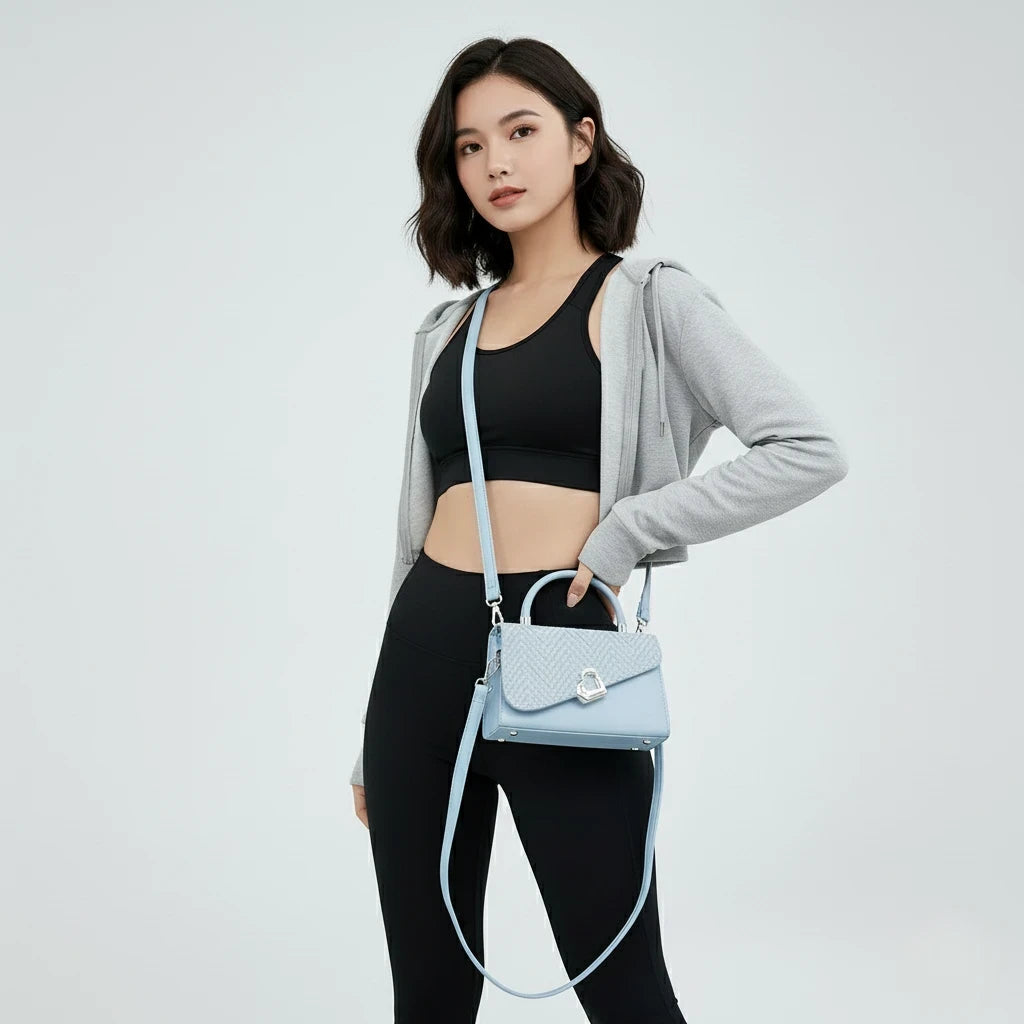 Woman holding a light blue handbag against a plain background