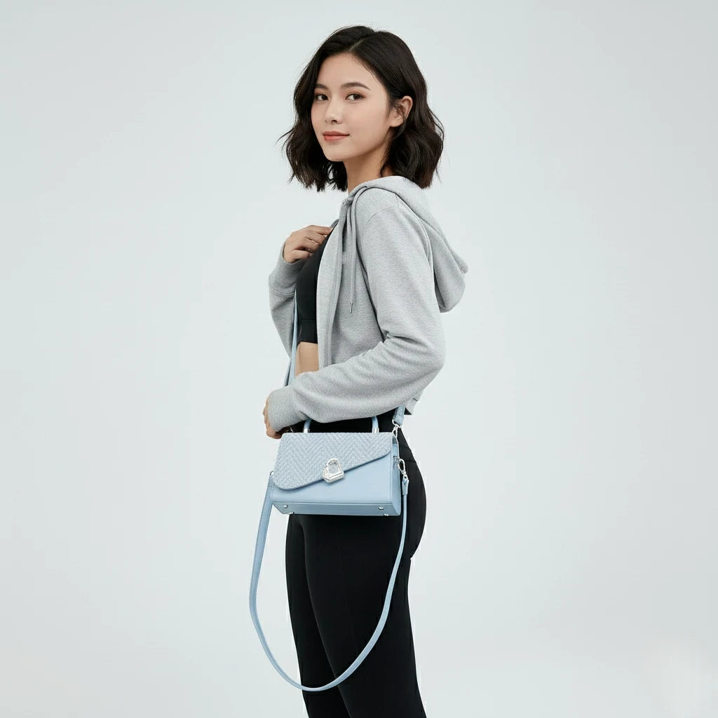 Woman holding a light blue handbag against a white background