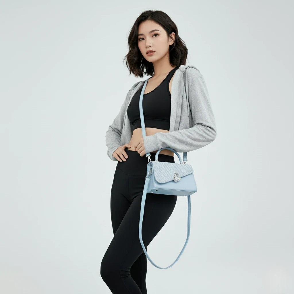 Woman holding a light blue handbag against a plain background