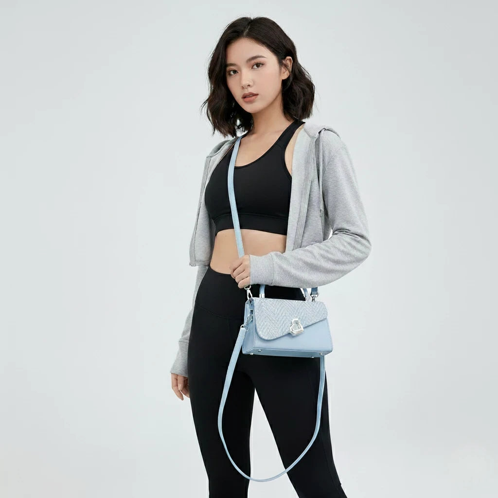 Woman holding a light blue handbag against a plain background