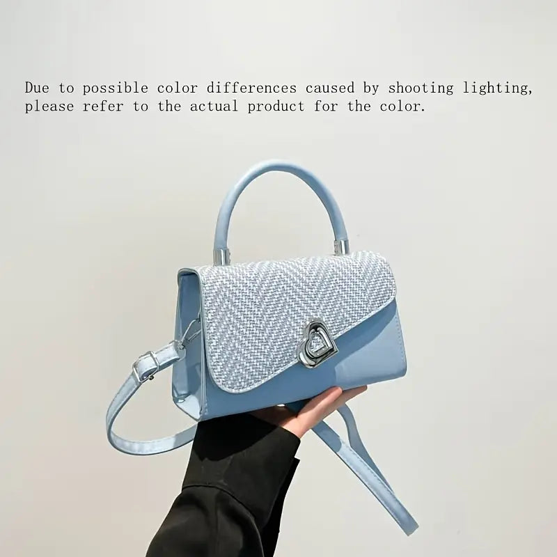Light blue handbag held by a person against a plain background