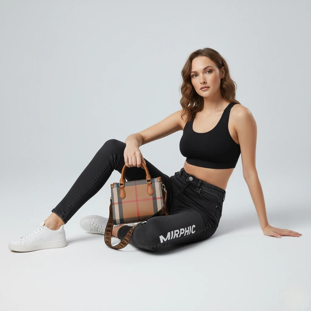 Woman sitting on the ground holding a checkered handbag, wearing a black sports bra and jeans with 'MIRPHIC' branding.
