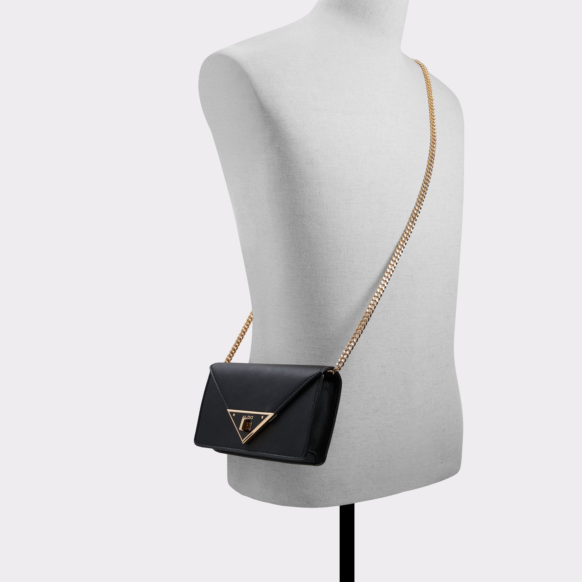 Black handbag with gold chain strap on a mannequin against a white background