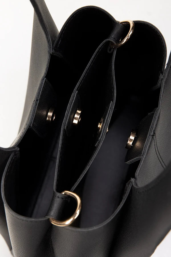Close-up of a black handbag with gold accents on a white background