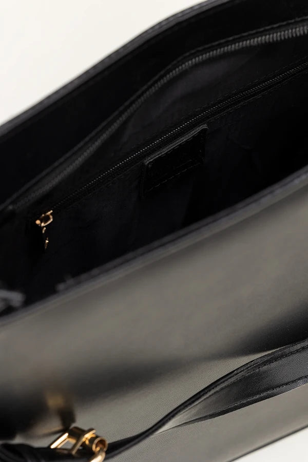 Close-up of a black handbag with a gold clasp on a white background