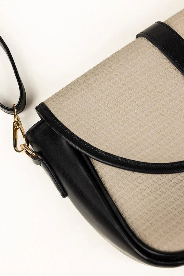 Close-up of a beige handbag with black accents on a white background