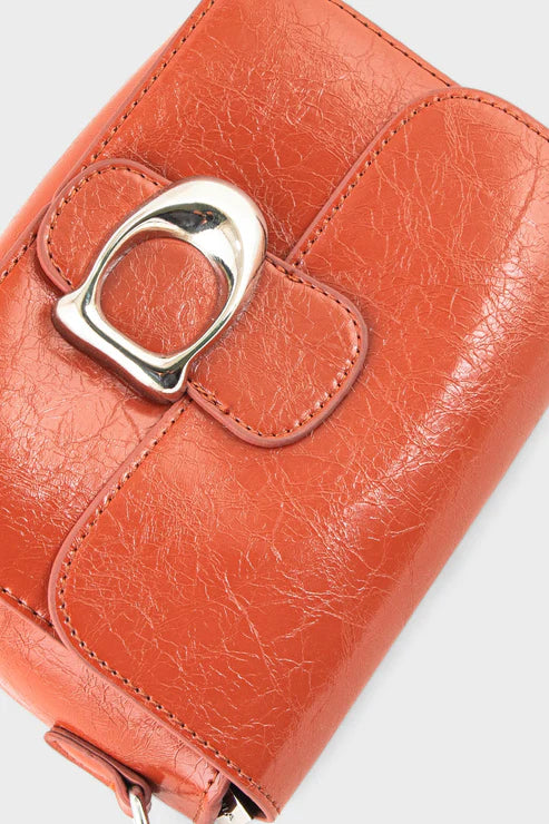 Close-up of an orange leather wallet with a silver buckle on a white background
