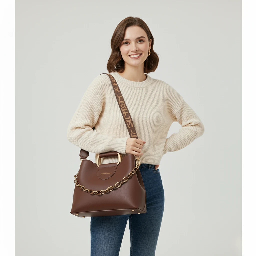 Woman holding a brown handbag with gold chain detail against a light gray background