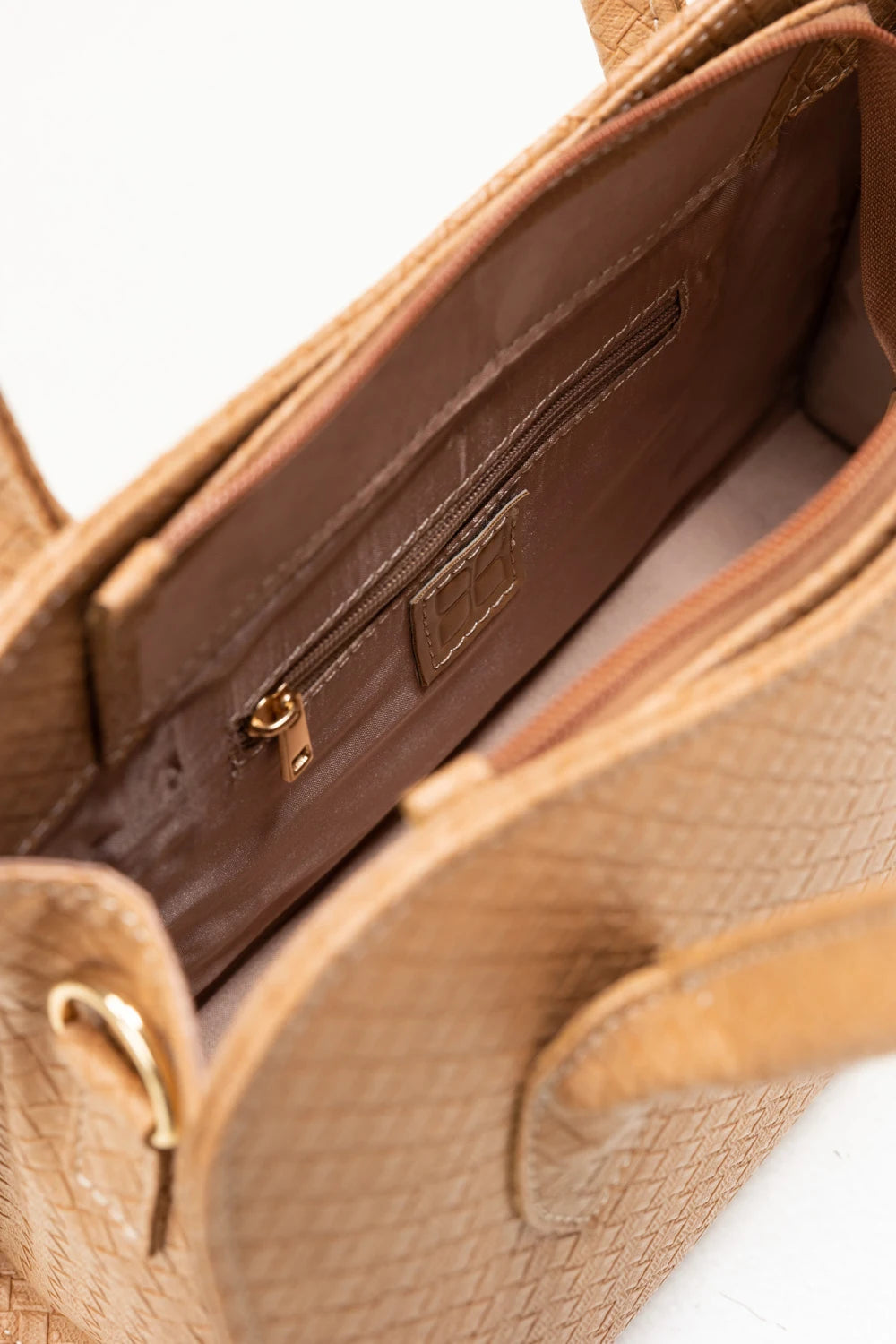 Close-up of a brown leather handbag with gold hardware on a white background