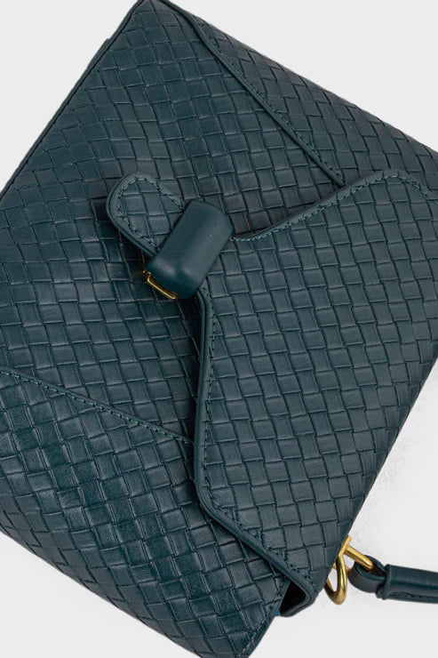 Teal woven handbag with a strap on a light gray background