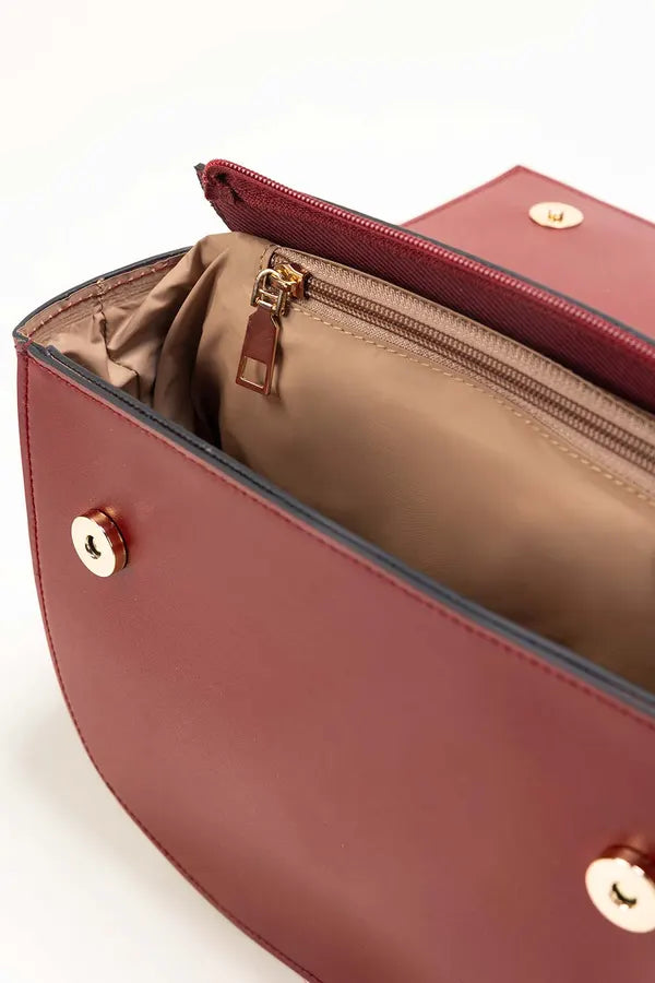 Close-up of a red handbag with gold hardware on a white background