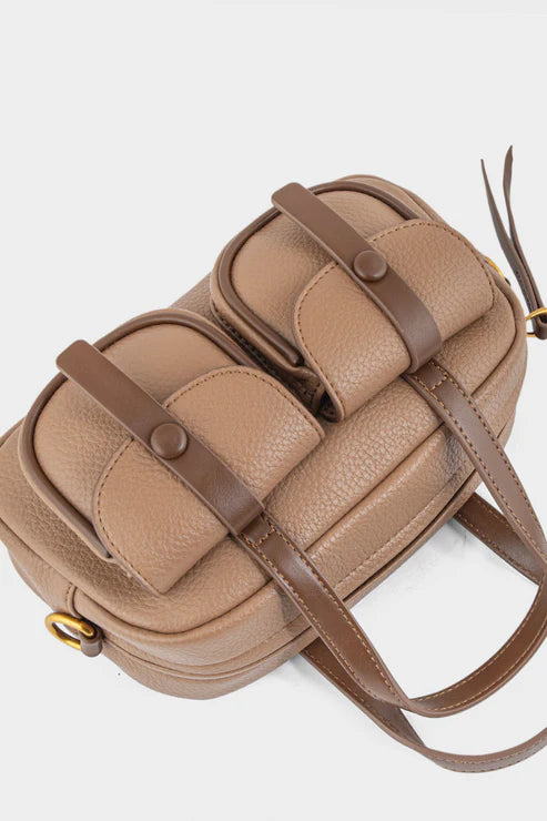 Beige handbag with brown straps on a light gray background