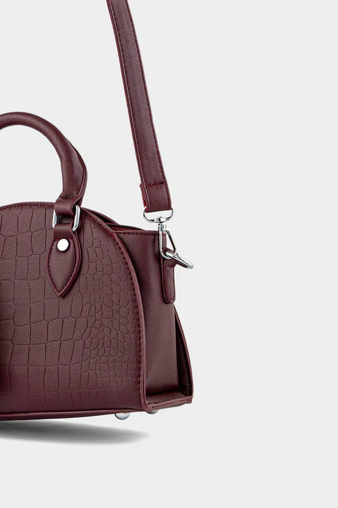 Maroon handbag with a textured pattern on a light gray background