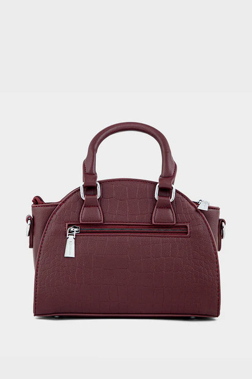 Maroon handbag with silver zippers on a light gray background