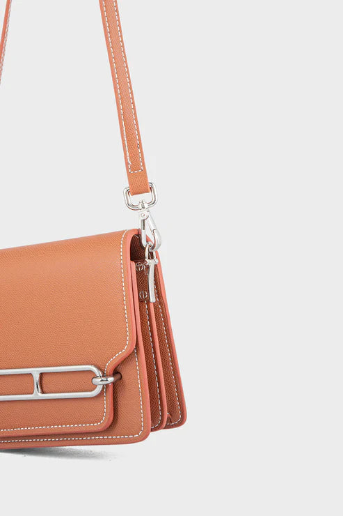 Brown handbag with silver accents on a light gray background