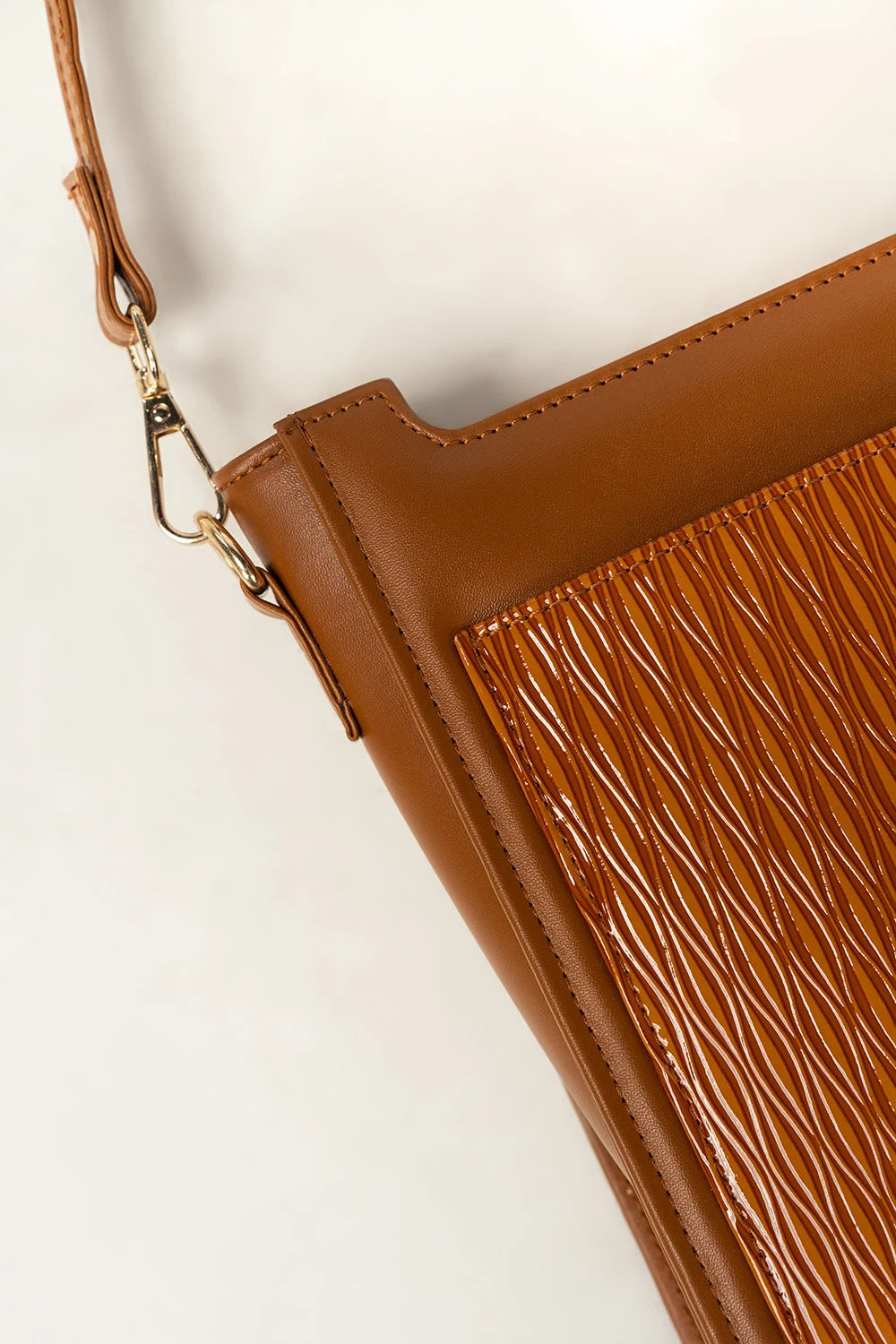 Brown textured handbag with a strap on a light beige background