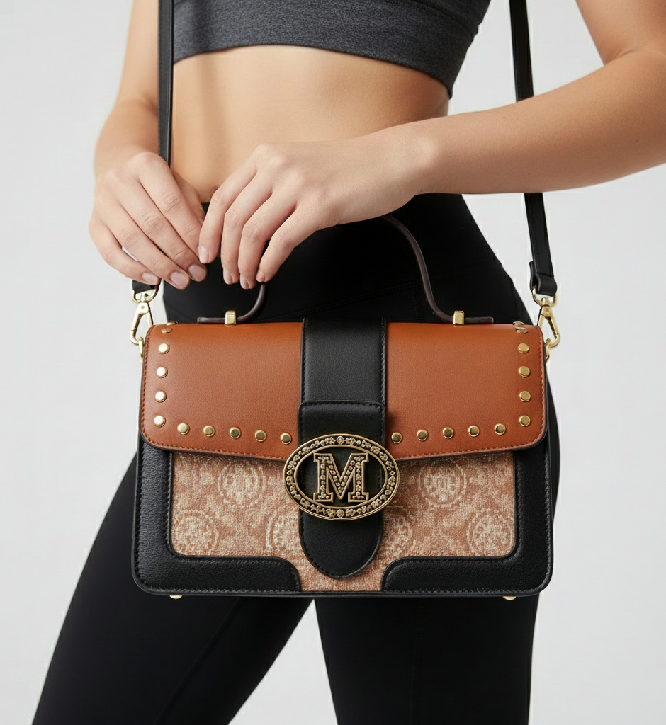 Handbag with decorative clasp held by a person against a neutral background