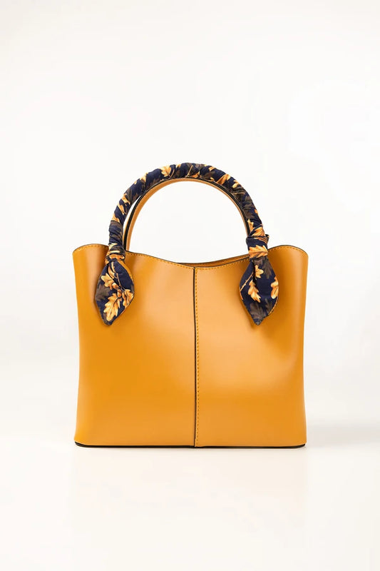 Yellow handbag with decorative handles on a white background